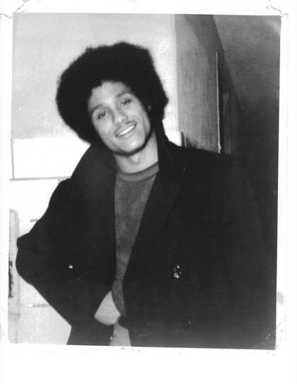 Black-and-white portrait of a smiling person in a dark jacket.